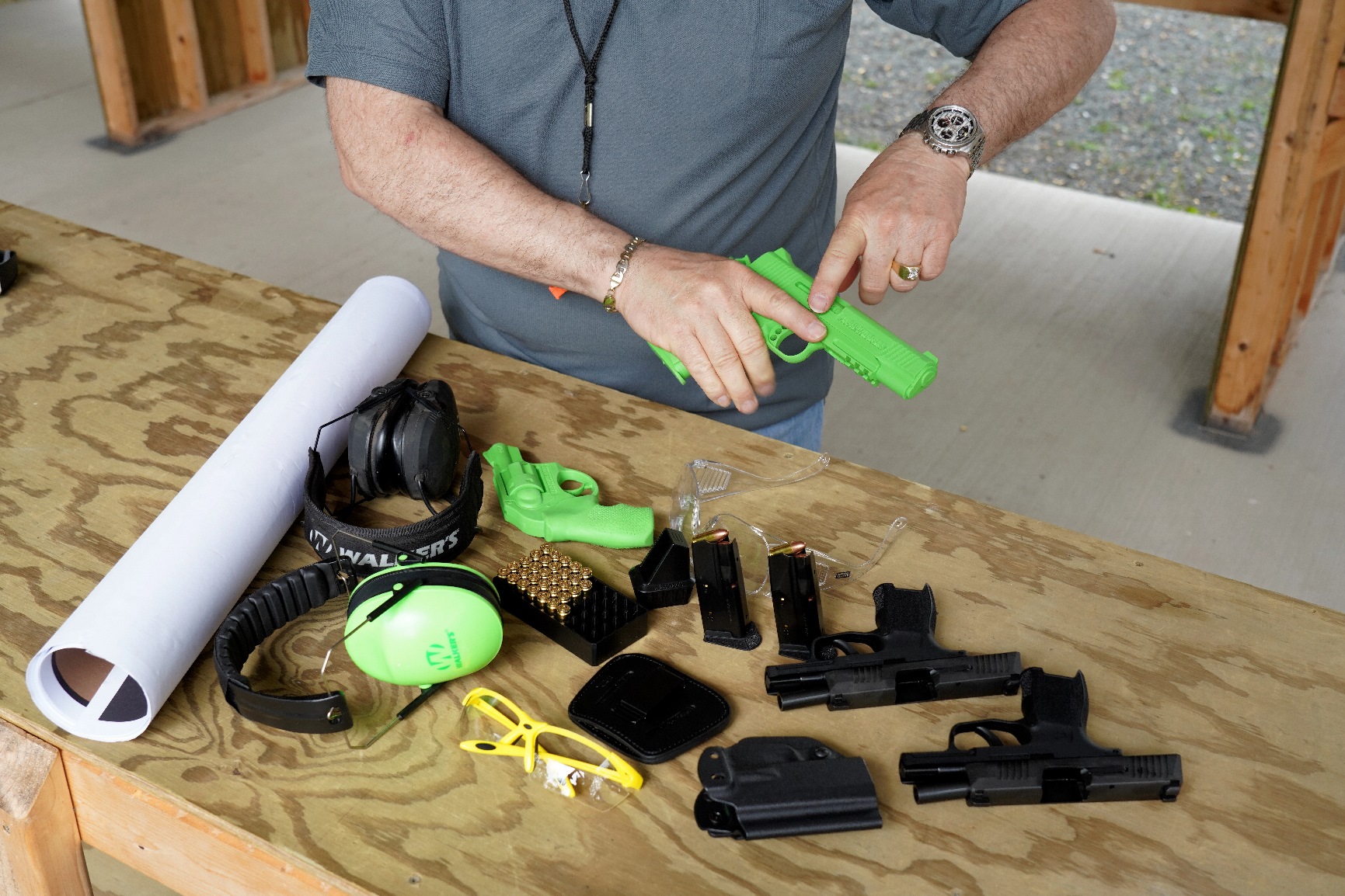 Man pointing at gun with gun accessories on a table in front of him