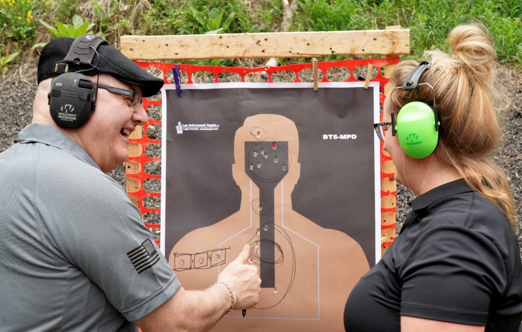 Man standing in front of shooting target giving woman thumbs up