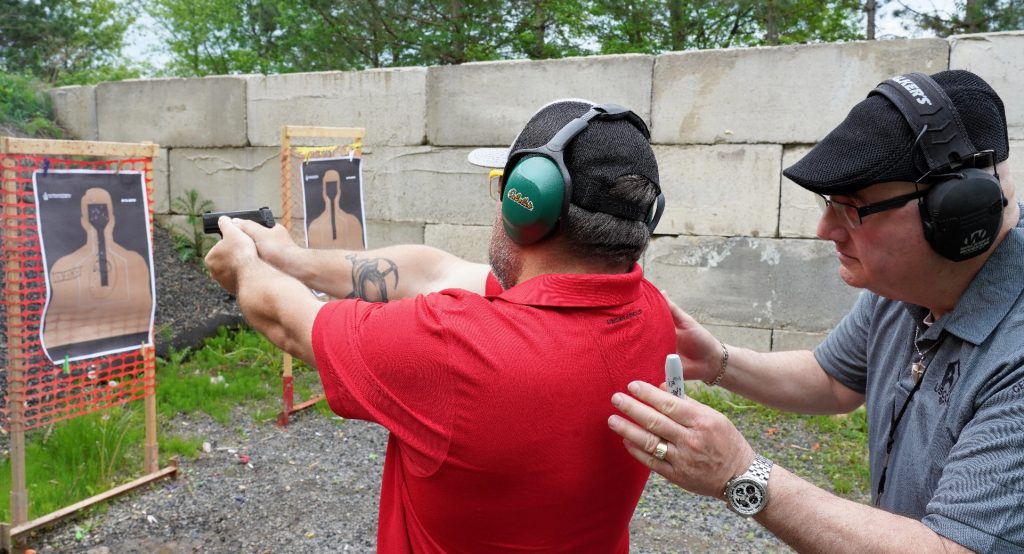 man crouched behind someone shooting gun